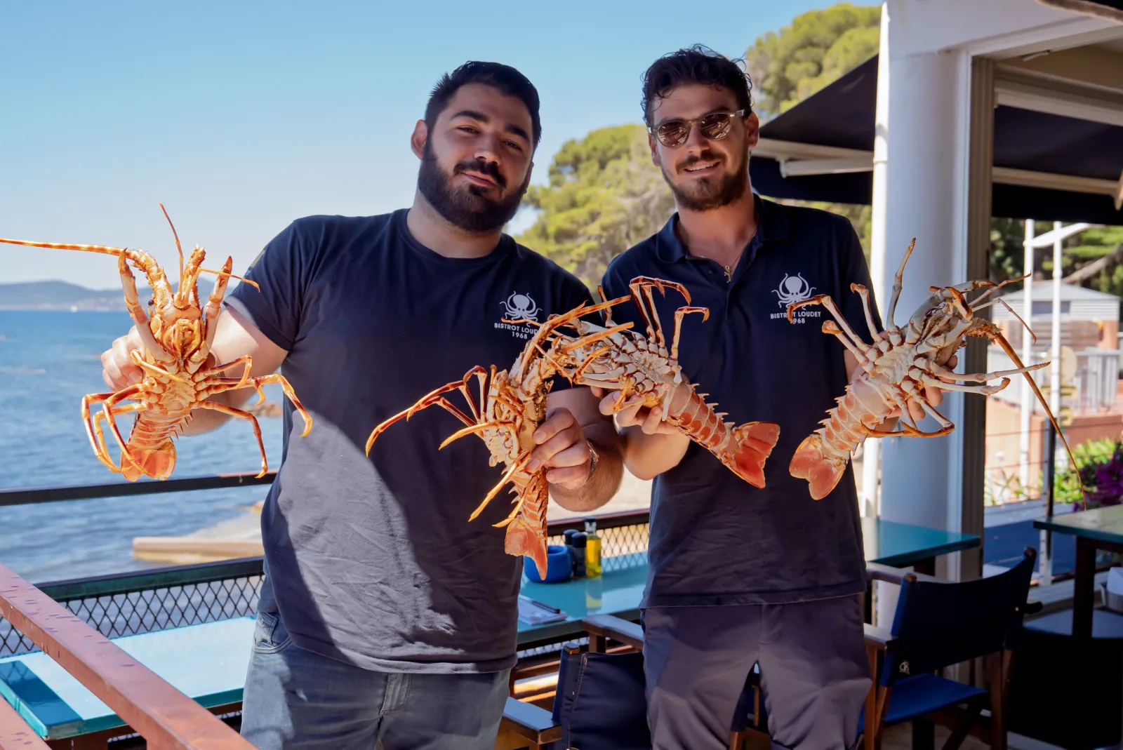 L'équipe du Bistrot Loudet présentant des langoustes en terrasse face à la mer à Saint-Raphaël